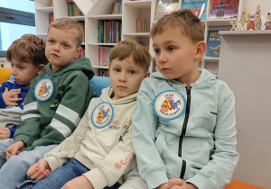 Chłopcy siedzą na kanapie z plakietkami z Kubusiem Puchatkiem.