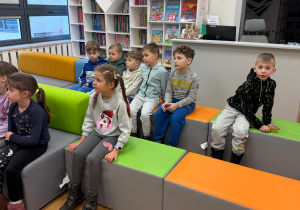 Dzieci siedzą w bibliotece na kanapach.