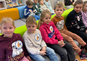 Dzieci siedzą na kanapie z przypinkami z Kubusiem Puchatkiem.