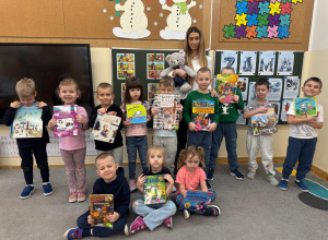 Dzieci pozują do wspólnego zdjęcia z nauczycielem, misiem i swoimi ulubionymi książeczkami.