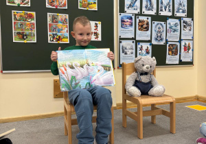Chłopiec prezentuje książkę i dzieli się jej treścią z grupą