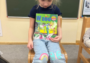 Dziewczynka z dumą pokazuje swoją ulubioną książkę dzieciom.