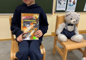 Chłopiec trzyma w ręku książkę.