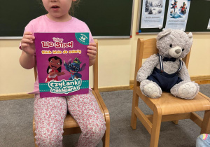 Dziewczynka opowiada o książce w towarzystwie projektowego Misia.