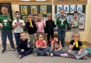 Dzieci pozują z otrzymanymi od nauczyciela zakładkami do książek.