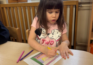 Dziewczynka z zaangażowaniem ozdabia okładkę do ulubionej historii.