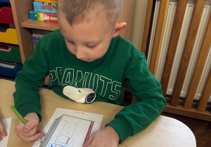 Chłopiec skupiony tworzy barwną okładkę.