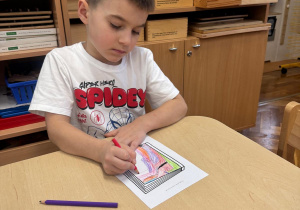 Chłopiec kończy swoją kolorową i pomysłową pracę.