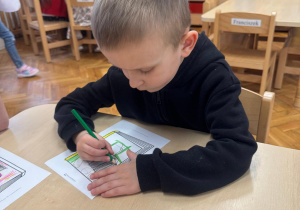 Chłopiec rysuje postaci na okładce swojej książki.