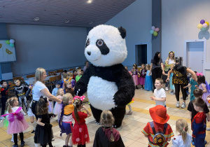 Dzieci tańczą w kole z pandą.