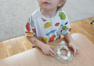 27. Chłopiec dekoruje pączka.