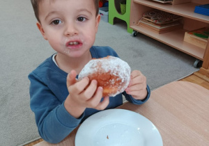 32. Chłopiec je pączka.