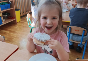 33. Dziewczynka je pączka.