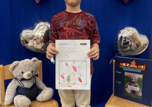 Uśmiechnięty uczestnik projektu prezentuje swoją kartę z dzienniczka.