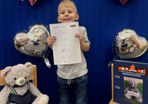 Uśmiechnięty uczestnik projektu prezentuje swoją kartę z dzienniczka.