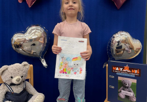 Uśmiechnięta uczestniczka projektu prezentuje swoją ilustrację.