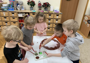 Dzieci malują farbami papierowego pączka.