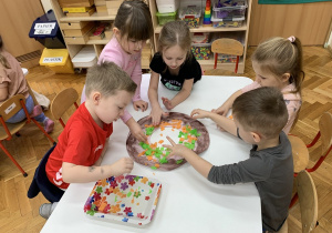 Czterolatki wyklejają bibułą papierowego pączka.