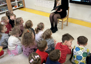 Dzieci uważnie słuchają pani bibliotekarki.