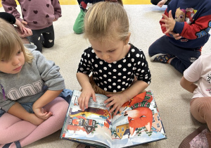 Dziewczynka ogląda książeczkę dla dzieci.