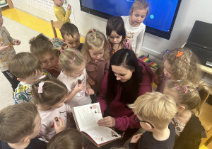 Dzieci ogladają ksiażkę podarowaną przez panią Paulinę.