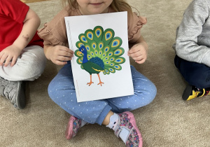 Dziewczynka z ilustracją pawia - wyjaśnienie przysłowia ,,Dumny jak paw".