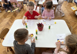 Dzieci wklejają Brawojkę do książeczek.