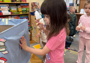 Dziewczynka tworzy kosmiczną dekorację, umieszczając swoją rakietę na statku.