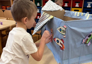 Chłopiec przygotowuje statek do startu, dodając swoją rakietę.