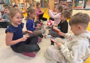 Dzieci grają na patyczkach podczas zabawy muzycznej.