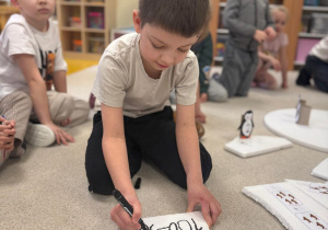 Chłopiec zapisuje działanie matematyczne.