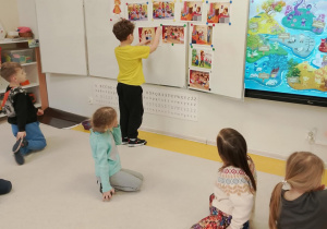 Chłopiec zawiesza obrazek na tablicy.