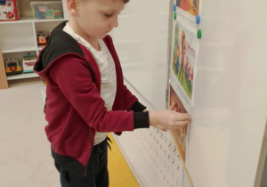 Chłopiec umieszcza na tablicy obrazek z opowiadania.