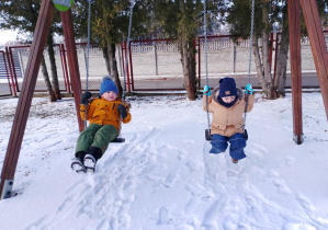 Dzieci huśtają się na huśtawkach.