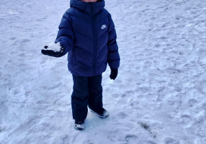 Chłopiec ze śnieżką w ręce.