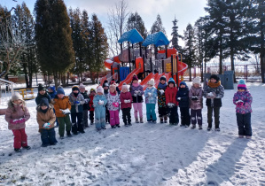 Dzieci ze śniegiem w rękach pozują do zdjęcia.