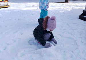 Dziewczynka zbiera śnieg.