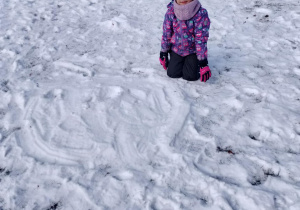 Dziewczynka rysuje w śniegu.