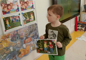 Chłopiec zawiesza na tablicy obrazek.