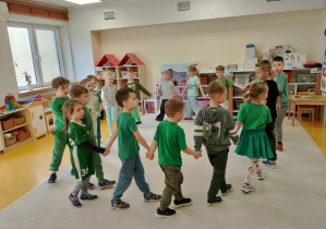 Dzieci ubrane na zielone tańczą w kole.