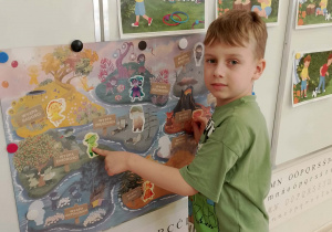 Chłopiec zawiesił postać Pana Zielonki na plakacie projektu.