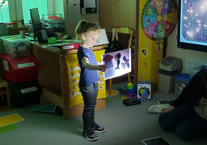 Dziewczynka trzyma w ręku orazek podświetlony przez latarkę.