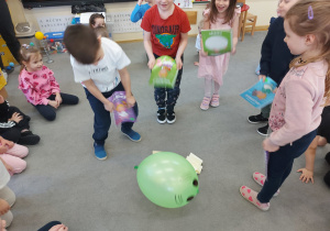 Dzieci bawią się ufoludkiem wykonanym z balonu.