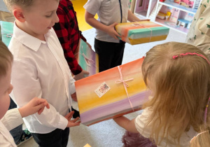 Chłopcy wręczają dziewczynkom upominki.