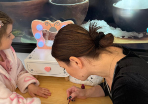 Pani maluje dziewczynce paznokcie.