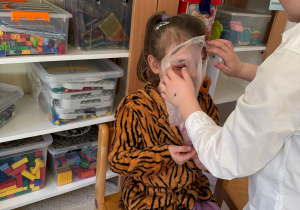 Chłopiec nakłada maseczkę koleżance.