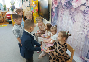 Chłopcy wręczają upominki dziewczynkom.