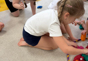 Dzieci chodzą na czworaka z woreczkami na karku.