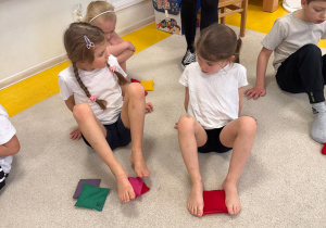 Dzieci przenoszą woreczki za pomocą stóp.