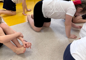 Dzieci chodzą na czworaka z woreczkami na karku.